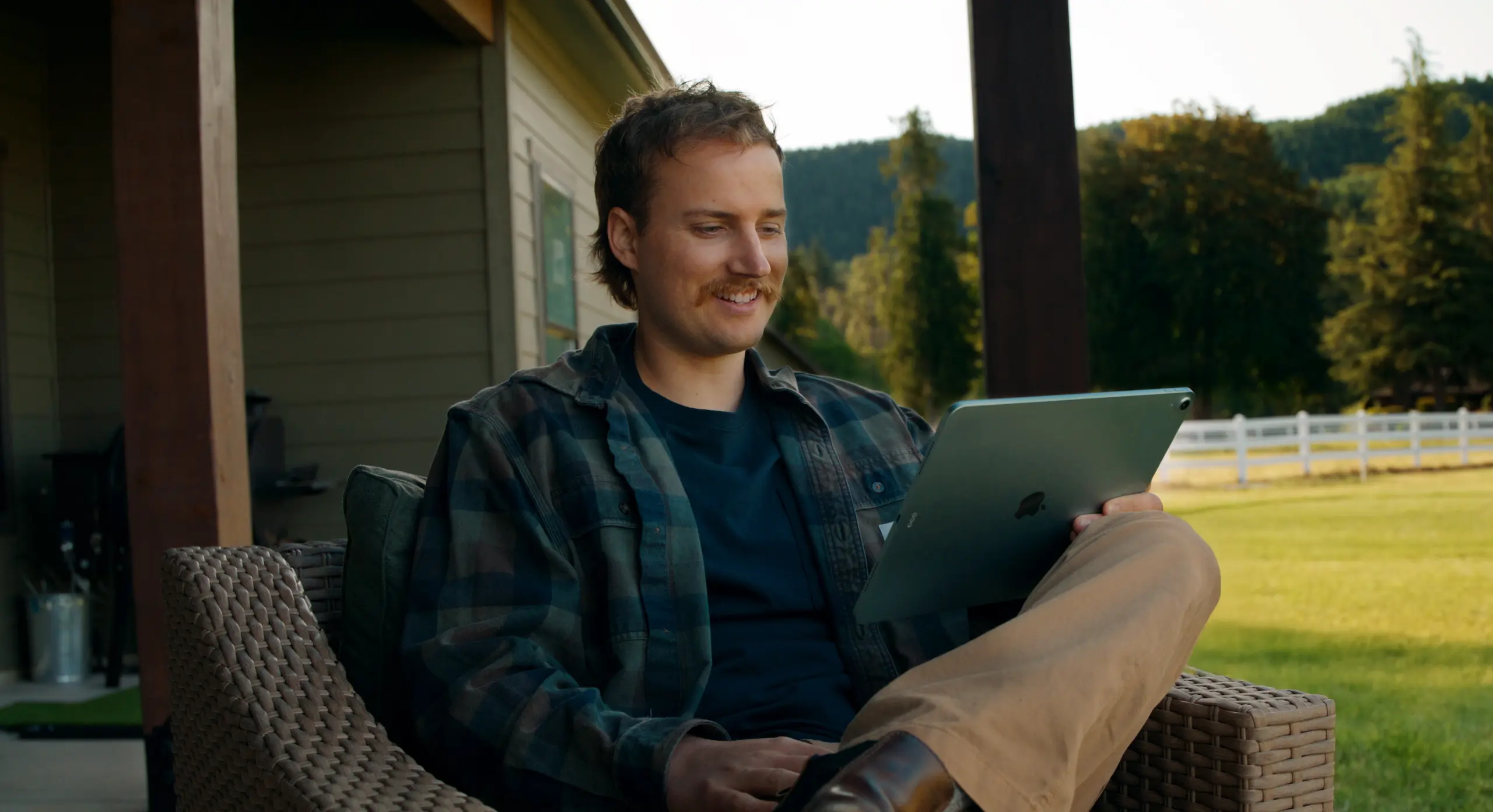 Man smiling using tablet on porch