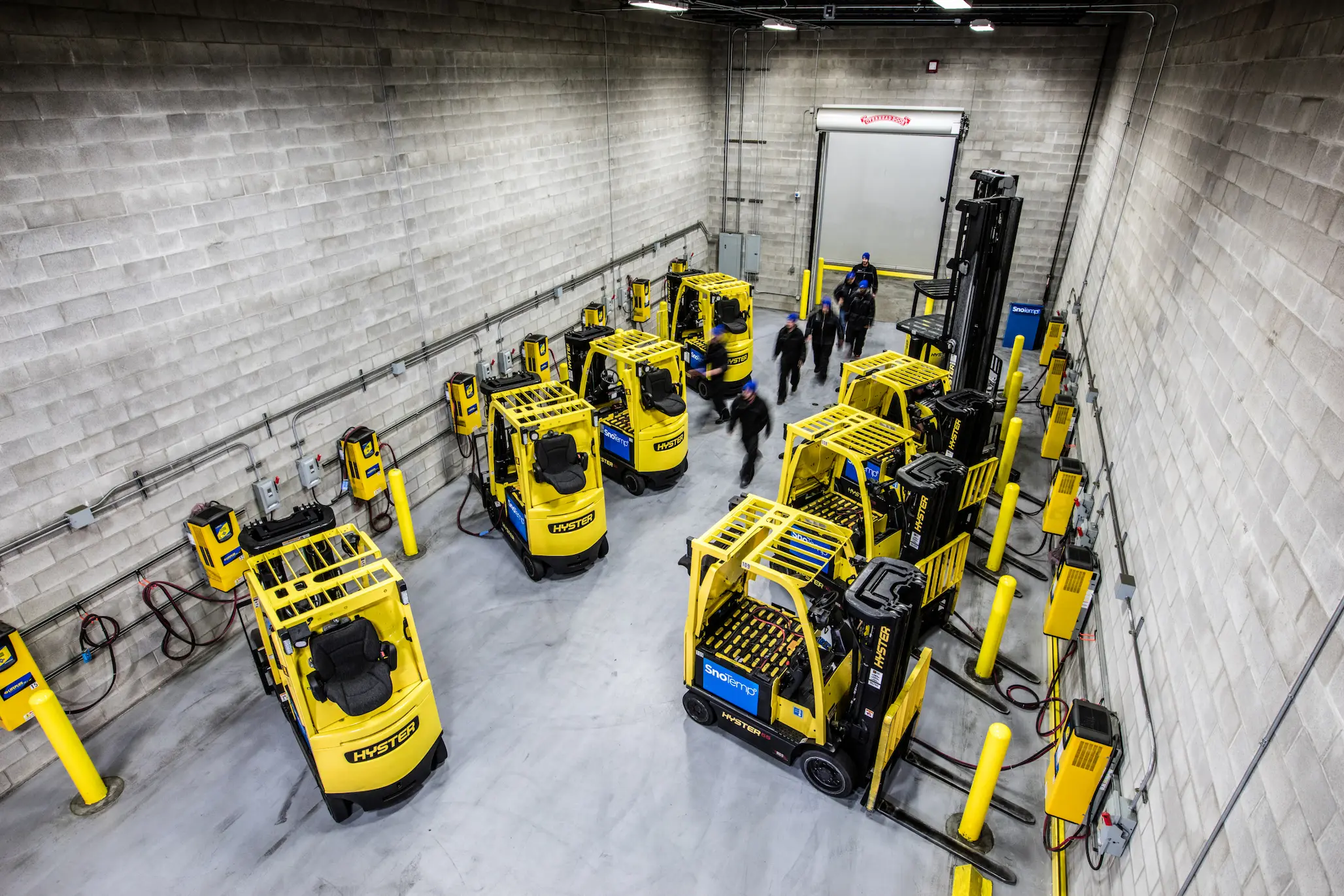 Fleet of Hyster forklifts charging indoors