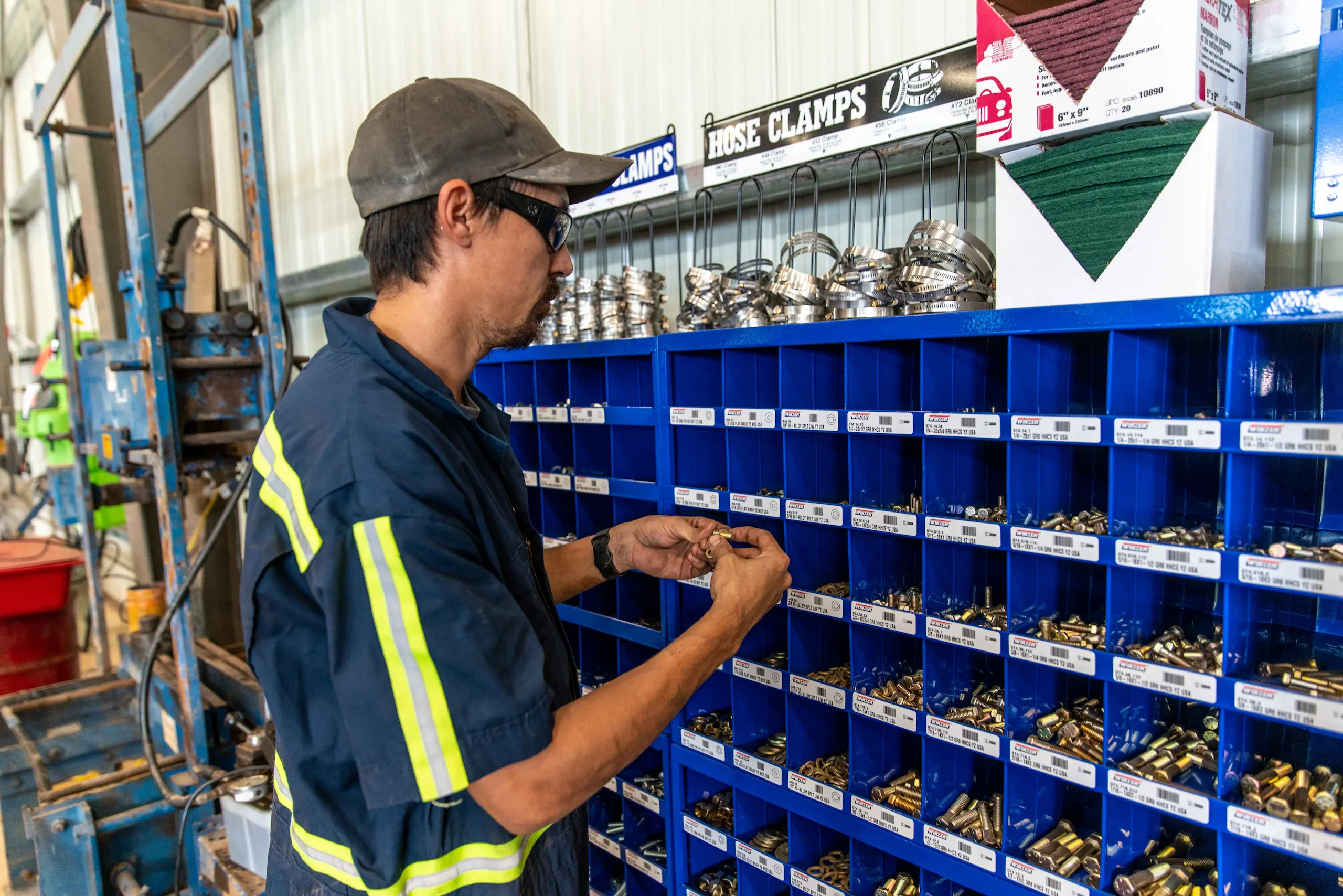 Worker selecting bolts from parts bins