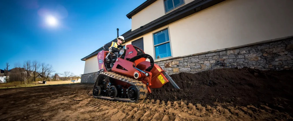 Ditch Witch mini loader digging by house