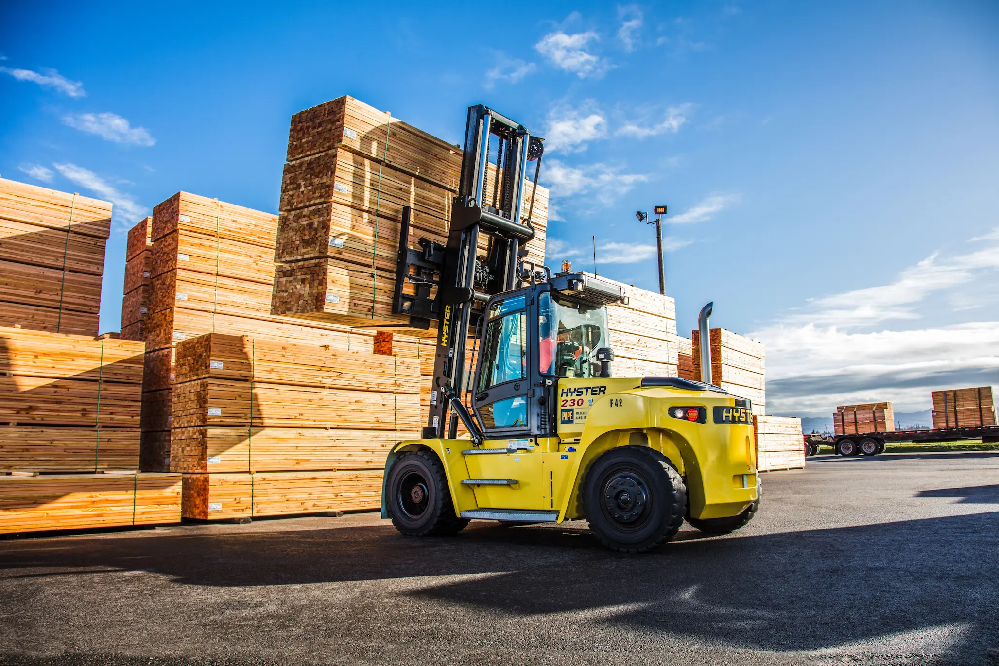 Hyster forklift moving stacked lumber outdoors