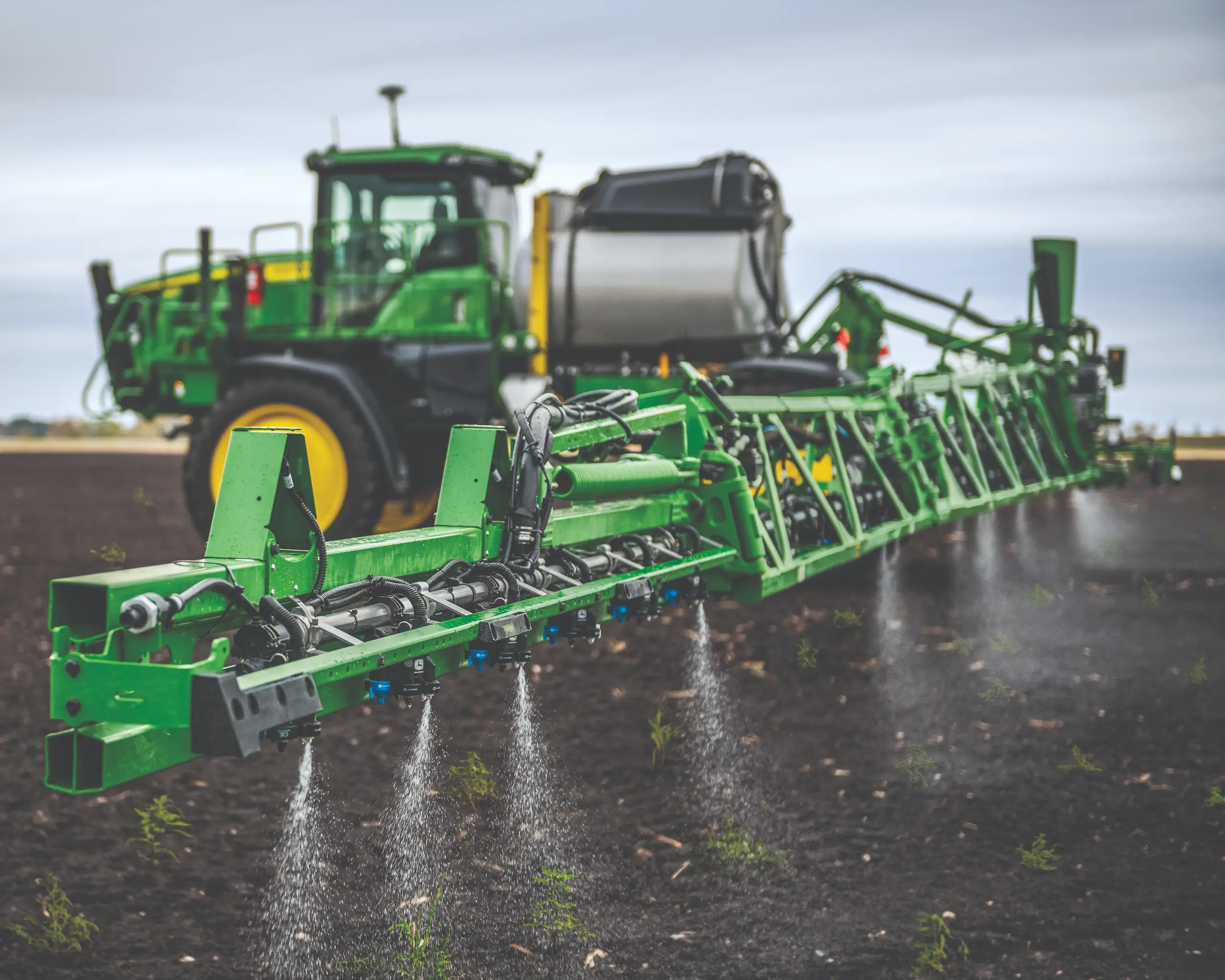 Sprayer boom spraying crops in field
