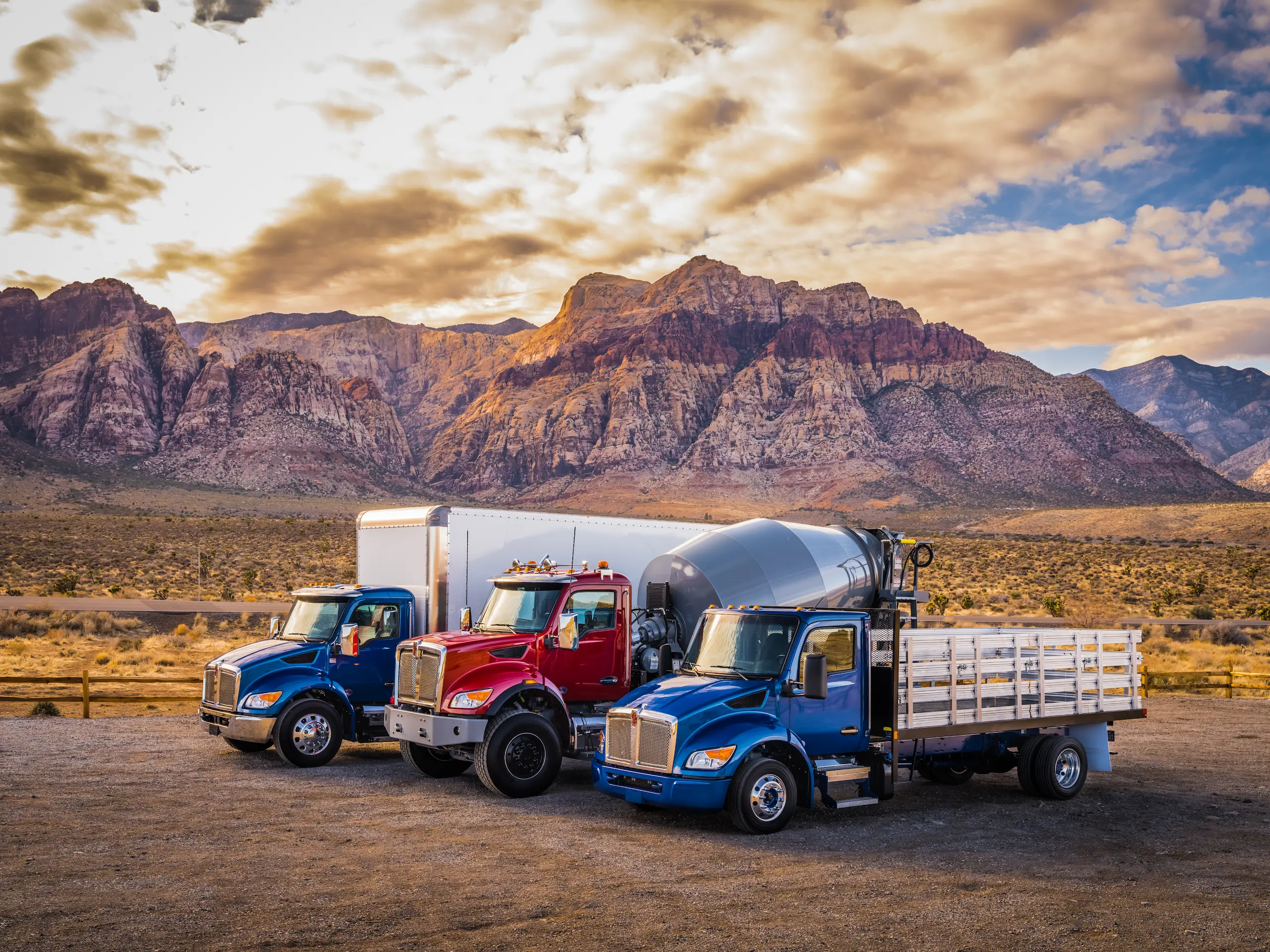 Three Kenworth work trucks near mountains