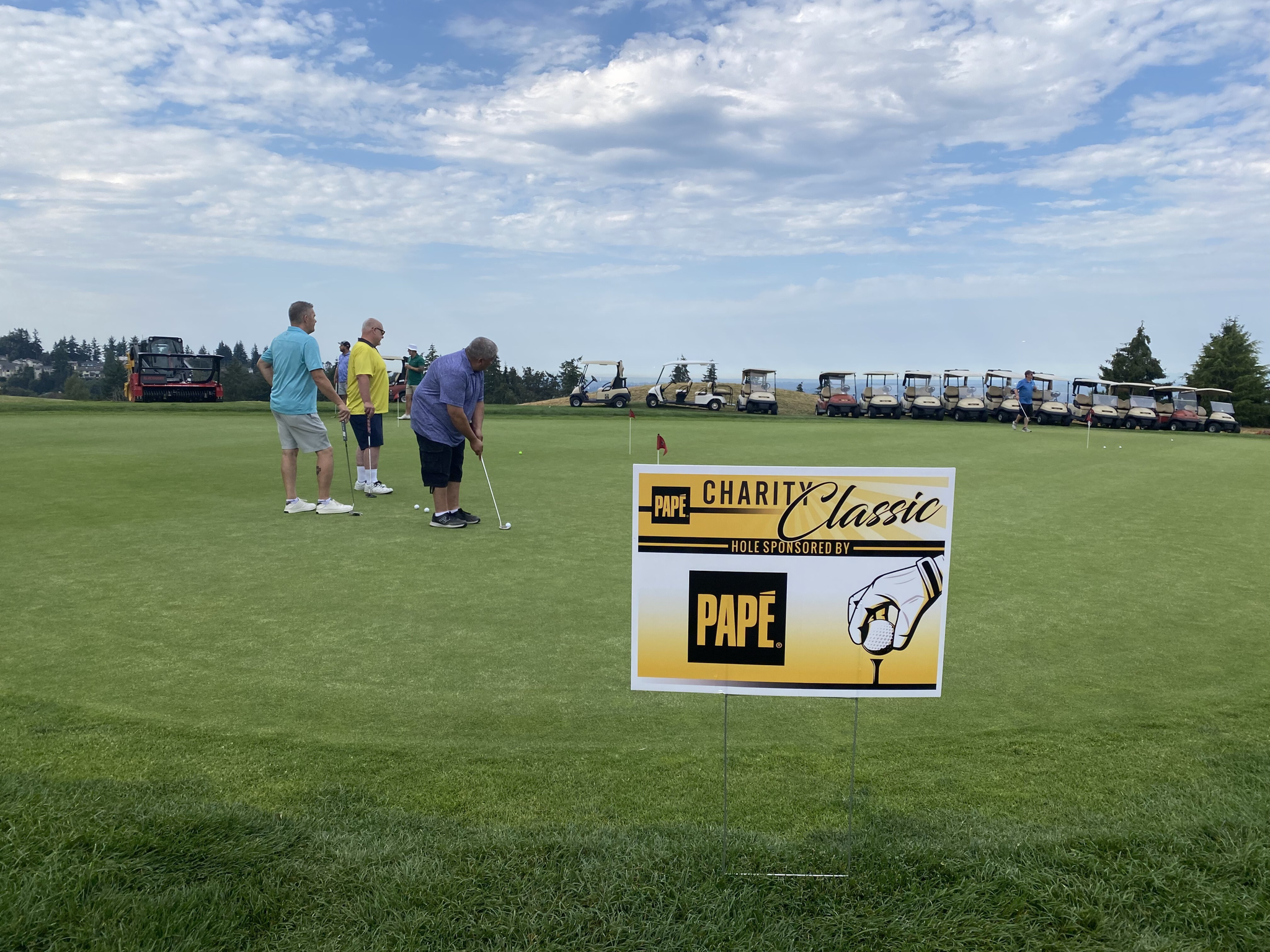 Golfers putting near Papé Charity Classic sign