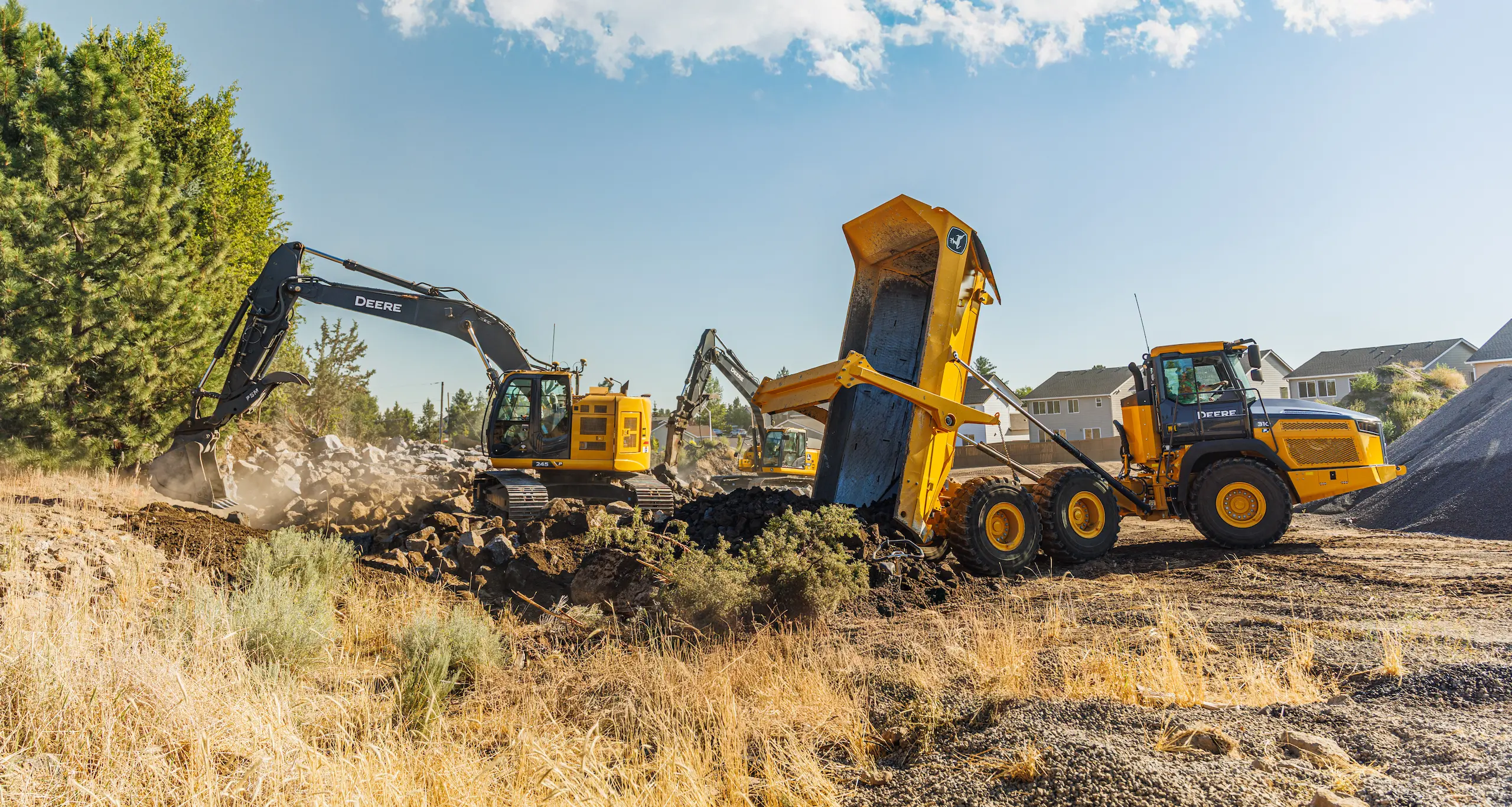John Deere excavators dumping rock debris