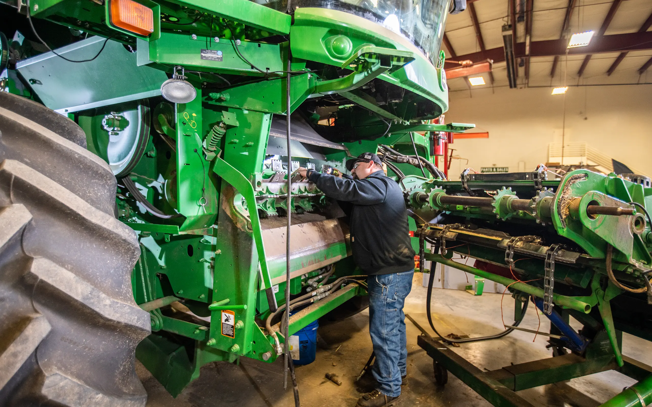 Technician repairing combine harvester in shop