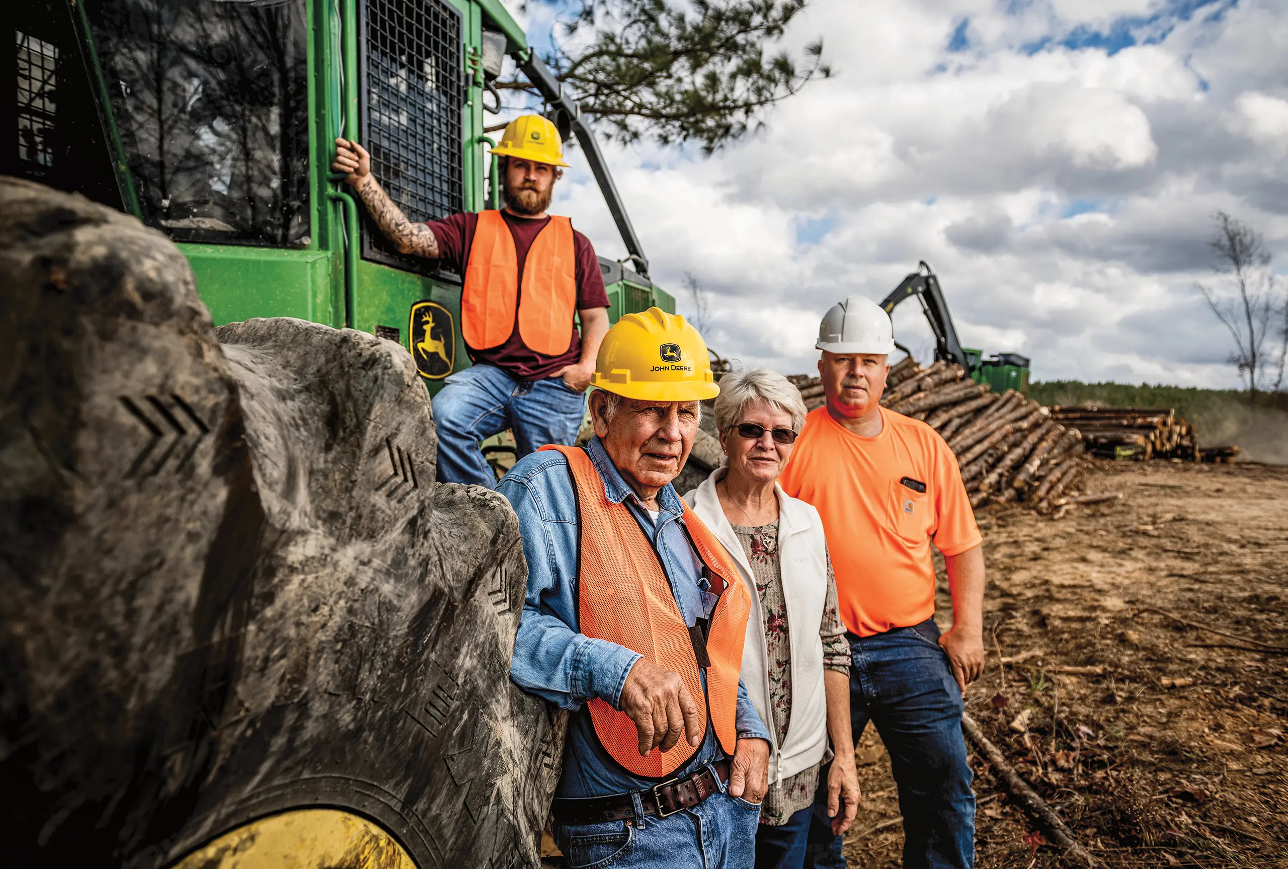 Workers standing beside John Deere skidder