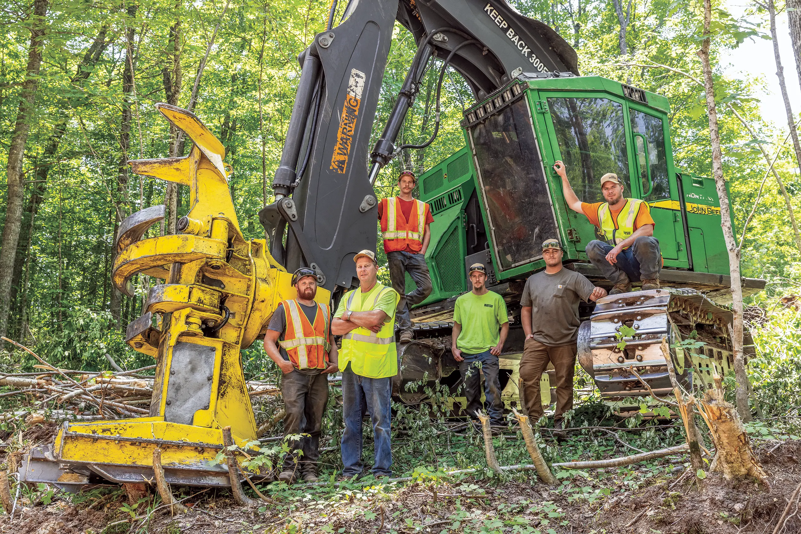 Logging crew posing by feller buncher