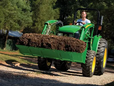 John Deere tractor hauling loose mulch