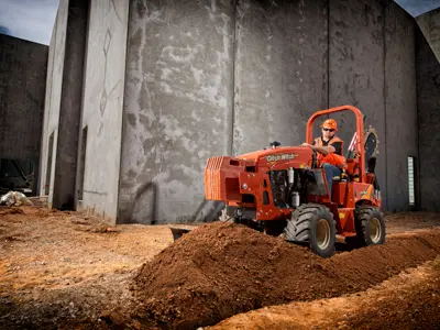 Ditch Witch trencher digging near wall