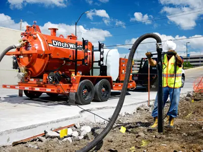 Worker operating vacuum excavation truck hose