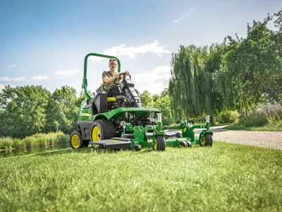 Man mowing grass on green mower