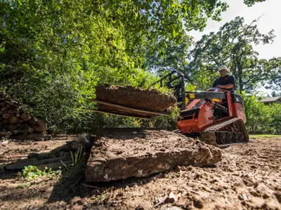 Mini skid steer moving log debris