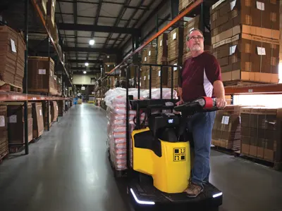 Man riding pallet jack in warehouse