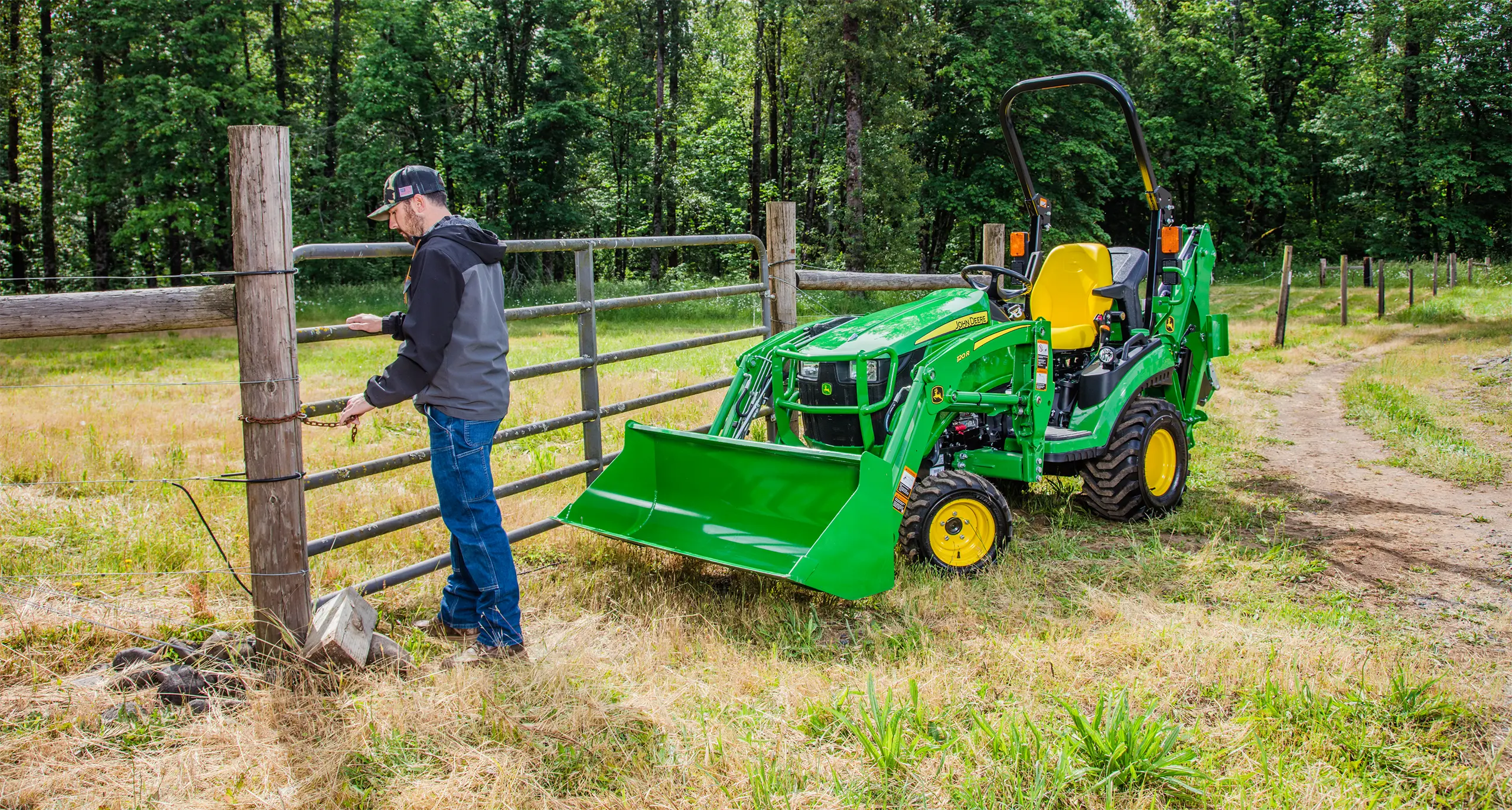 Man opening gate near green tractor