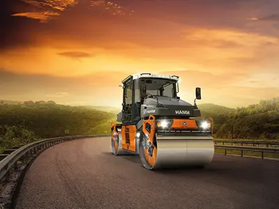 Road roller on highway at sunset