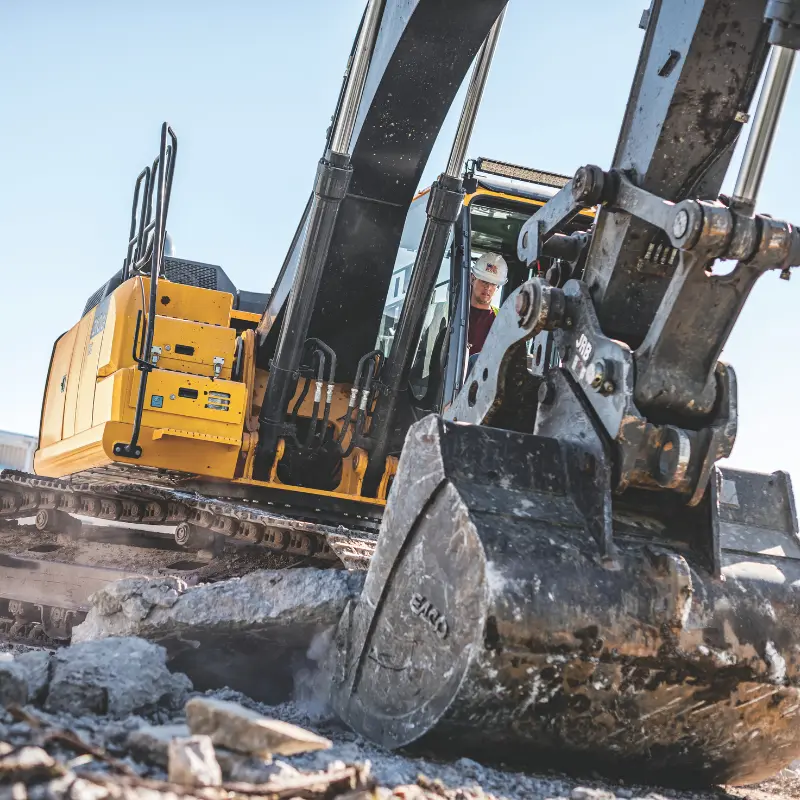 Excavator operator breaking concrete with bucket