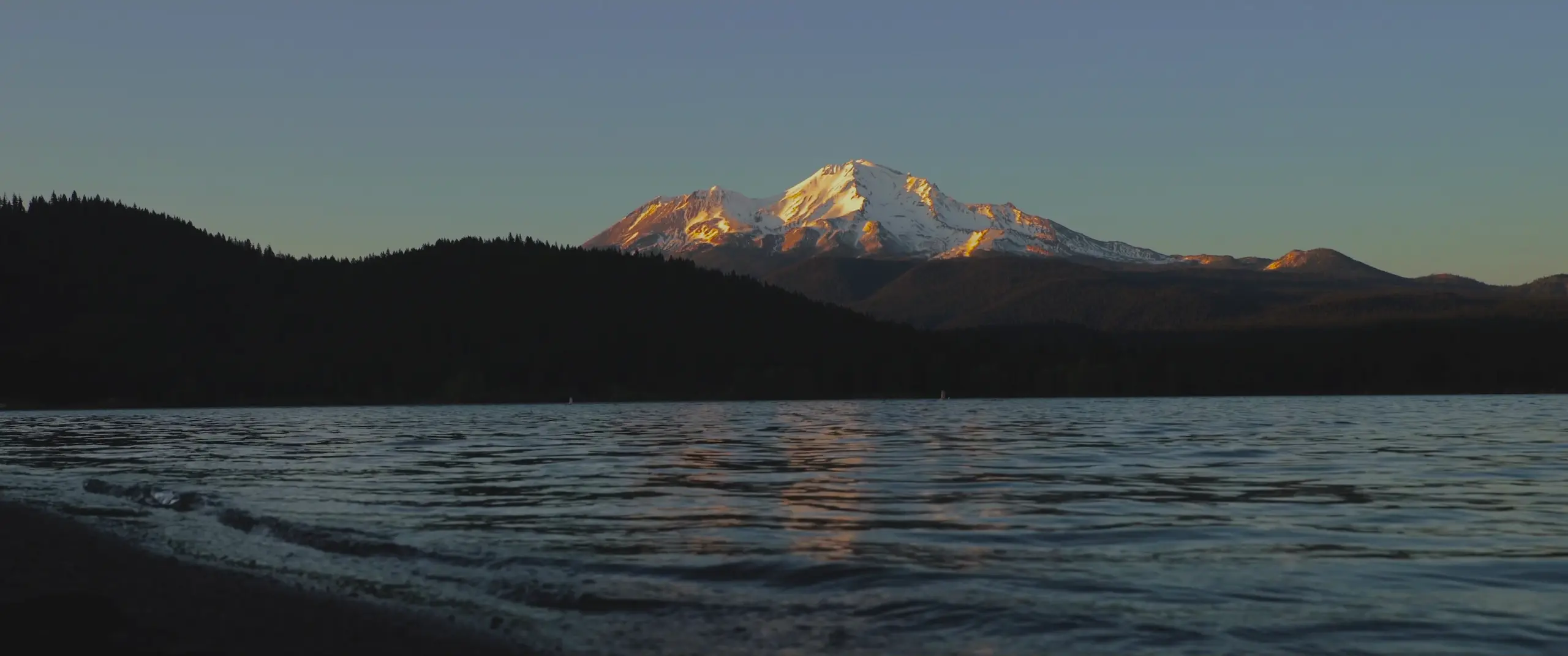 Snow-capped mountain glowing over lake