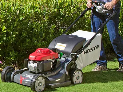 Man pushing Honda lawn mower outside