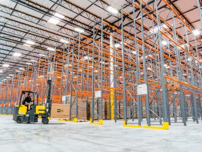 Forklift among tall warehouse racks