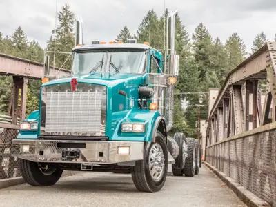 Teal semi truck crossing metal bridge